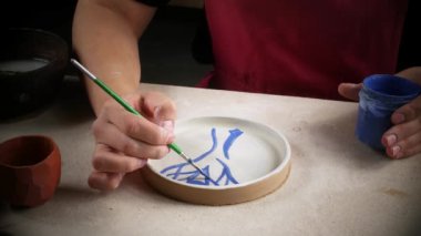 Craftsman yeni yapılmış bir boya plakası süsler. Atölyede çalışma.
