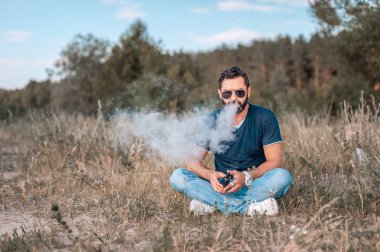 Sakallı vaper bir çift bir vape havaya uçurrıyor. Sağlık kavramı.