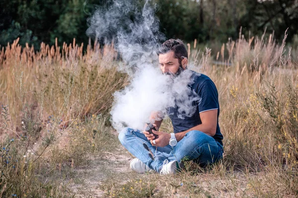 Un uomo moderno che si gode una sigaretta elettronica. All'uomo piace molto il processo di fumo. . — Foto Stock