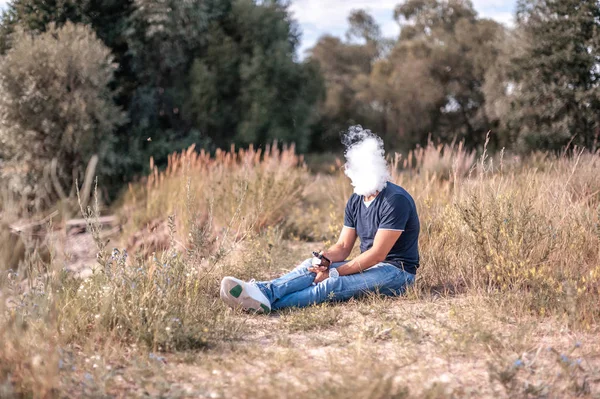 Elegante barbuto vaper fa saltare in aria un paio di una sigaretta elettronica all'aperto. Non fumatori di tabacco . — Foto Stock