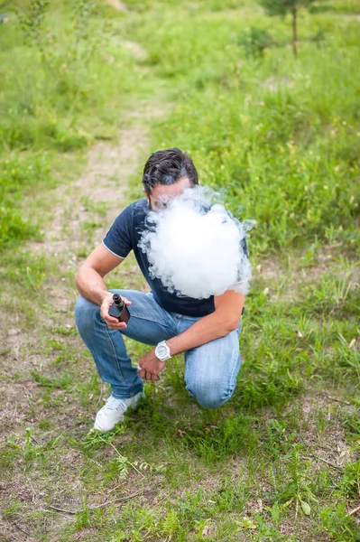 Şık sakallı sigara içen elektronik duman cihaz ormanda duman dışarı nefes sigara. Hibrid sigara. — Stok fotoğraf