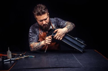 İşyerinde yeni deri ürünü üzerinde çalışırken deri ile çalışan sanatçı