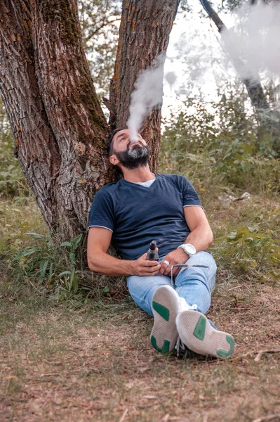 Moderno vaper godendo di una sigaretta elettronica in natura. Sigaretta elettronica concetto . — Foto Stock