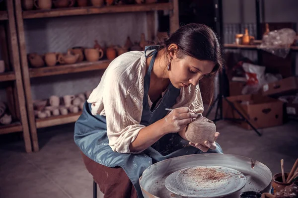 Stilvolle Keramikbildhauerin arbeitet mit Ton an der Töpferscheibe und am Tisch mit den Werkzeugen. Inspiration und Kreativität. — Stockfoto