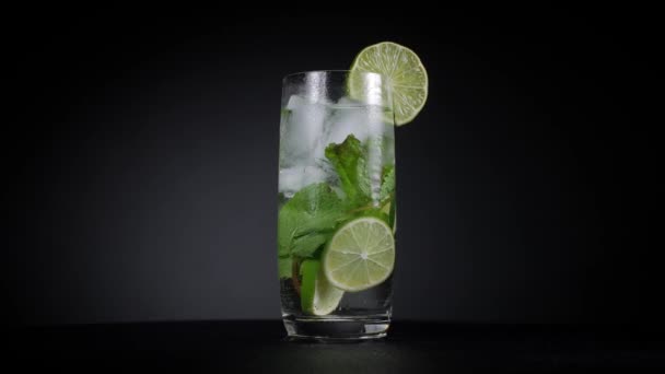 Kall cocktail med lime och mynta på svart bakgrund. — Stockvideo