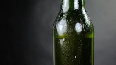 Siyah bir arka plan üzerinde taze demlenmiş soğuk bira yeşil bir şişe. Bir ışık ışını onu güzelce aydınlatır. Yavaşça döner..