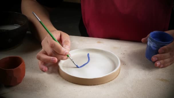 A craftswoman in a workshop paints a freshly prepared plate. Handwork — Stock Video