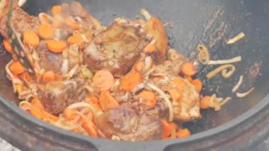 Büyük bir kazanda gerçek Özbek pilavı. Ulusal yemekler pişirmek. Geleneksel pilav pişirme. Ulusal yemeklerin hazırlanması