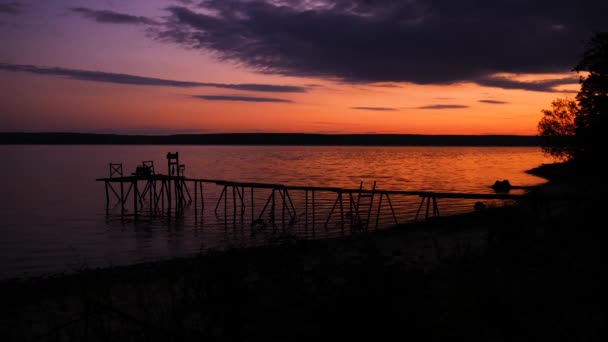 Inställningen solen hällde färg i kvälls vattnet. Bron ledde till en magisk natt värld. — Stockvideo