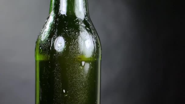 Garrafa de cerveja fria com gotas, geada em preto — Vídeo de Stock