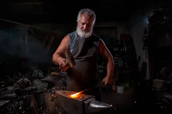 Blacksmith with brush handles the molten metal