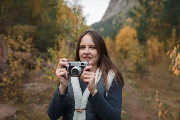 Portrait of a girl with a retro camera on the background of autumn mountains