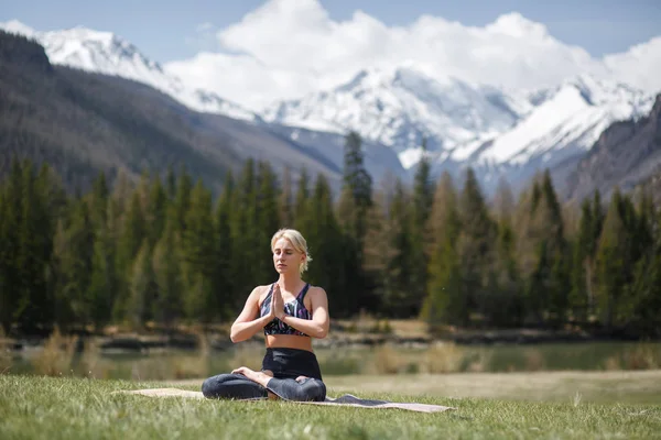 Young woman doing yoga in outdoor. Happy girl enjoy beautiful mountain and good weather