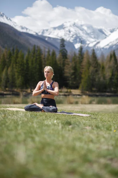 Young woman doing yoga in outdoor. Happy girl enjoy beautiful mountain and good weather