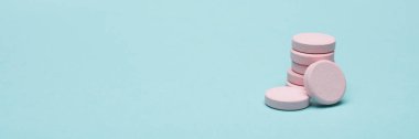Mavi pastel renkli arka plan üzerinde pembe Doğum kontrol hapları. Web afiş kopya alanı ile ilaç ve besin takviyeleri.