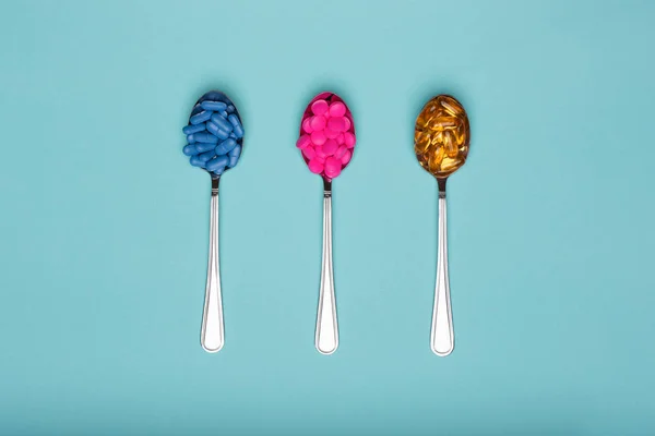 Table Spoons Filled Assortment Various Colourful Pills Isolated Blue Pastel — Stock Photo, Image