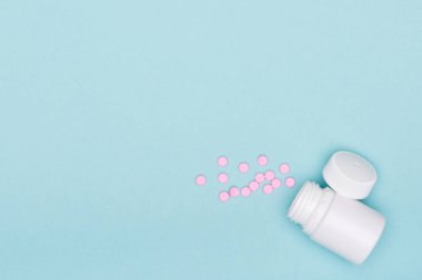İlaç şişe ve beyaz hap mavi pastel renkli arka plan üzerinde döktüm. İlaç ve reçeteli ilaç düz arka plan yattı. Opioid salgın.