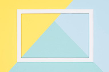 Soyut geometrik pastel mavi, yeşil ve sarı kağıt düz yatıyordu arka plan. Boş resim çerçevesini sahte kadar minimalizm, geometri ve simetri şablonuyla.