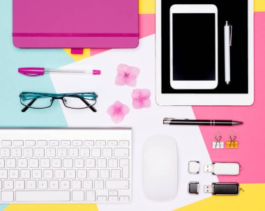 Ofis Masası çalışma alanı düz yatıyordu. Çalışma alanı boş sahte tablet ve smartphone, kahve fincanı, klavye ve çok renkli pastel arka plan üstünde not etmek ile fotoğrafı üstten görünüm.