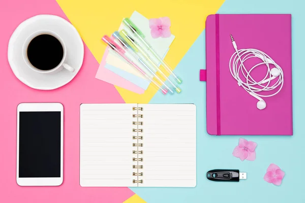 Office Desk Working Space Flat Lay. Top view photo of workspace with blank mock up smartphone, coffee cup and open notepad on pastel background. Pastel color working desk concept.