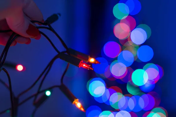 Female Hand Holding String Christmas Lights Defocused Xmas Tree Background — Stock Photo, Image