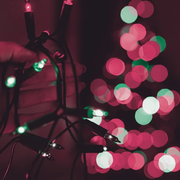 Femmina Mano Tenendo Stringa Luci Natale Con Albero Natale Sfocato — Foto Stock