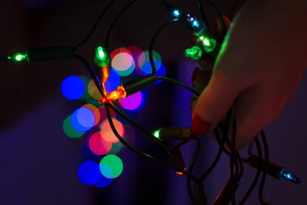 Female Hand Holding String Christmas Lights Defocused Xmas Tree Background — Stock Photo, Image