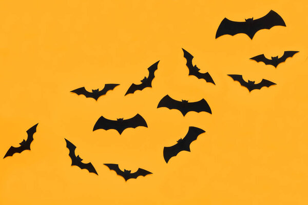 Хэллоуин и украшения концепции. Черные бумажные летучие мыши летят на оранжевом фоне. Хэллоуин
.