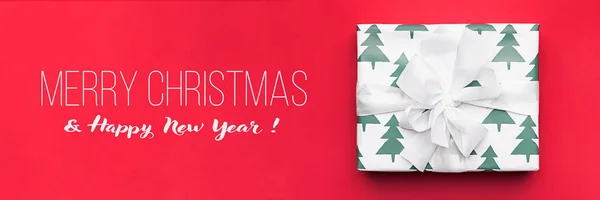 Christmas banner. Beautiful christmas gift isolated on red background. Wrapped xmas box. Gift wrapping concept.