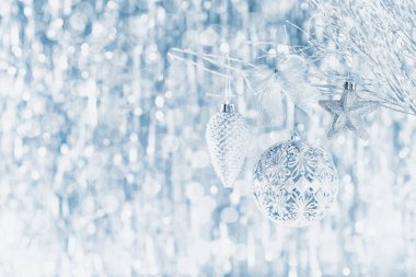 Arka planda ufuk Noel ışıkları ile bir ağaç üzerinde asılı parlak gümüş Noel süsler.