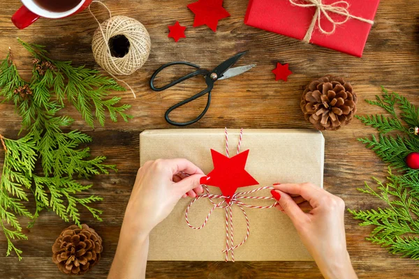 DIY Gift Wrapping. Woman wrapping beautiful red christmas gifts on rustic wooden table. Overhead point of view of christmas wrapping station.