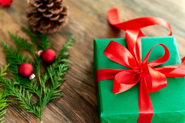 DIY Gift Wrapping. Beautiful green christmas gifts with red bow on rustic wooden table. Top view of christmas wrapping station.