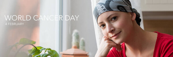 World Cancer Day Banner. Young positive adult female cancer patient sitting in the kitchen by a window, smiling and looking at the camera.