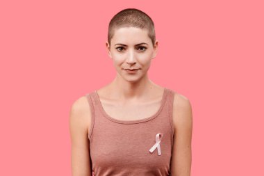 Mid 30s gülümseyen kadın, pembe meme kanseri bilinçlendirme şerit, yaşam içinde izole giyen bir kanser kurtulan mercan arka plan. Destek, dayanışma, tarama ve korunma kavramı.