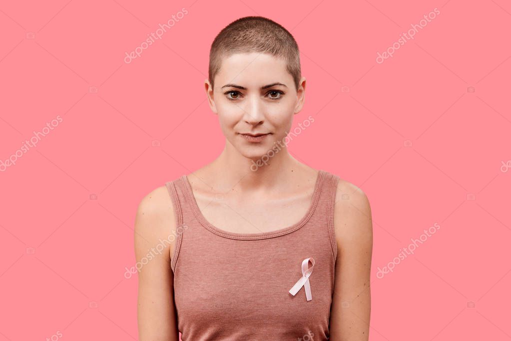 Mujer sonriente de 30 años, sobreviviente de cáncer, con cinta rosa de