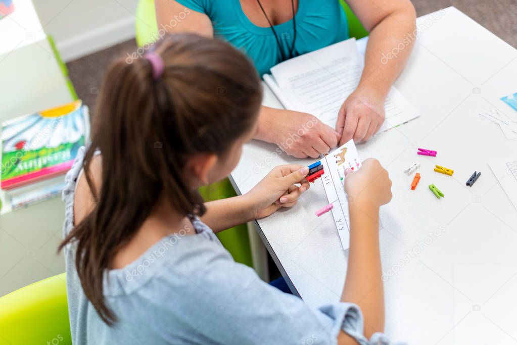 Mature female therapist working with a teenage girl with learning difficulties to master logical tests.