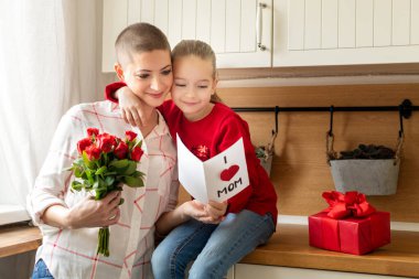 Sevimli genç kız ve annesi genç kanser hastası, ev yapımı bir tebrik kartı okuma. Aile kutlama kavramı. Mutlu anneler günü ya da doğum günü arka plan. 