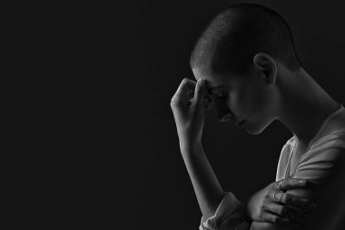 Sad, frightened and depressed female cancer patient portrait on dark background with copy space. Breast cancer patient, head in hands, black and white portrait. clipart