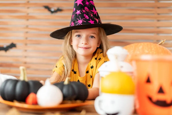 Cute Little Girl Noszenia Witch Hat Siedzi Stołem Halloween Dynie — Zdjęcie stockowe