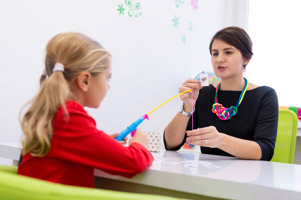 Elementary Age Girl in Child Occupational Therapy Session Doing Playful Exercises With Her Therapist. 