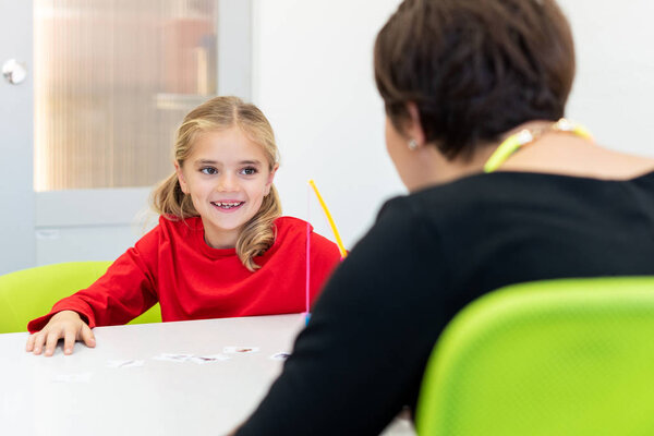 Elementary Age Girl in Child Occupational Therapy Session Doing Playful Exercises With Her Therapist. 