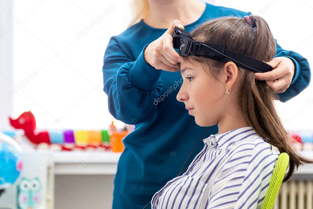 Young teenage girl and child therapist during EEG neurofeedback session. Electroencephalography concept. 