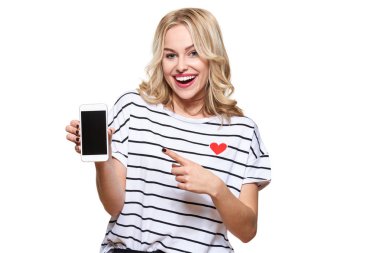 Muhteşem heyecanlı kadın beyaz arka planda cep telefonuyla boş ekrana işaret ederek zaferi ve başarıyı kutluyor. Heyecan, coşkulu duygu.