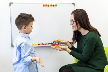 Çocuk konuşma terapisi konsepti. Konuşma terapisindeki anaokulu öğrencisi kadın bir konuşma terapistiyle nefes egzersizi yapıyor.. 
