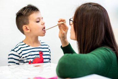 Çocuk konuşma terapisi konsepti. Anaokulu öğrencisi bir kadın konuşma terapistiyle doğru telaffuz pratiği yapıyor..