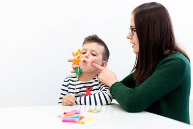 Çocuk konuşma terapisi konsepti. Anaokulu öğrencisi bir kadın konuşma terapistiyle doğru telaffuz pratiği yapıyor..