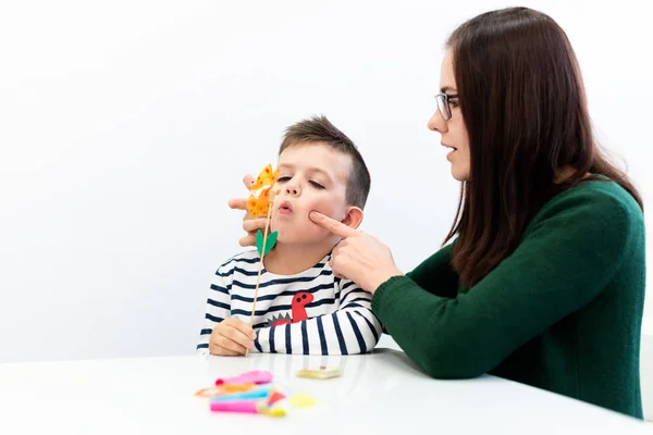 Children speech therapy concept. Preschooler practicing correct pronunciation with a female speech therapist.