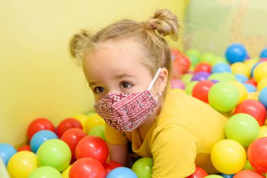 İş çocuk terapisi seansında oynarken yüz maskesi takan üç yaşında bir kız. Covid-19 salgın konsepti.