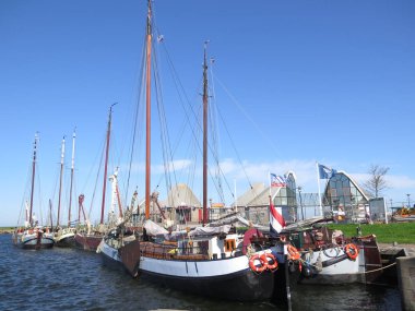 Stavoren, Hollanda - 23 Nisan 2018: Yelkenli tekneler Hollandalı balıkçı köyü güneşli bahar günü limanda palamarla