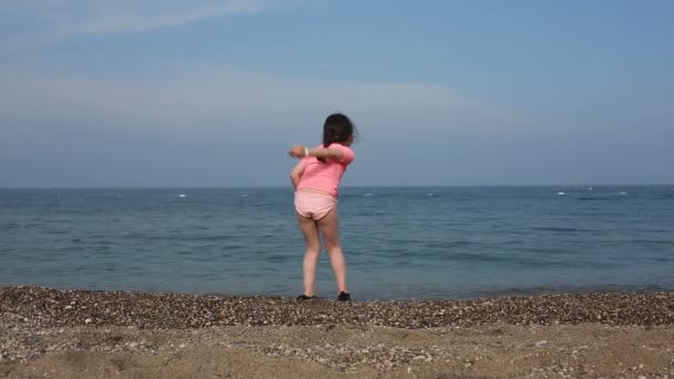 Hermosa chica arrojando piedras al mar — Vídeos de Stock